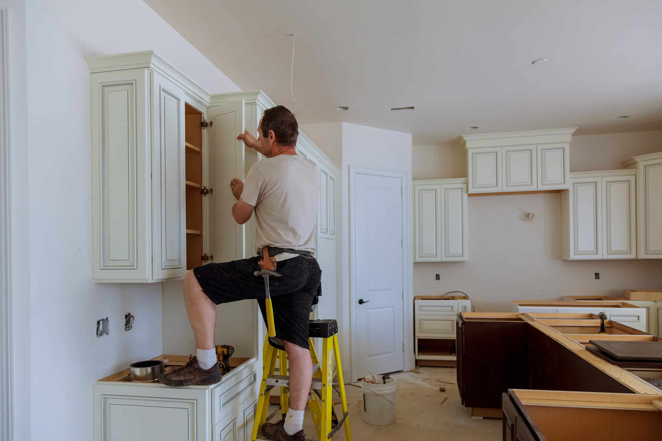 Man installing kitchen cabinets door installation of kitchen cabinet door replacement cost
