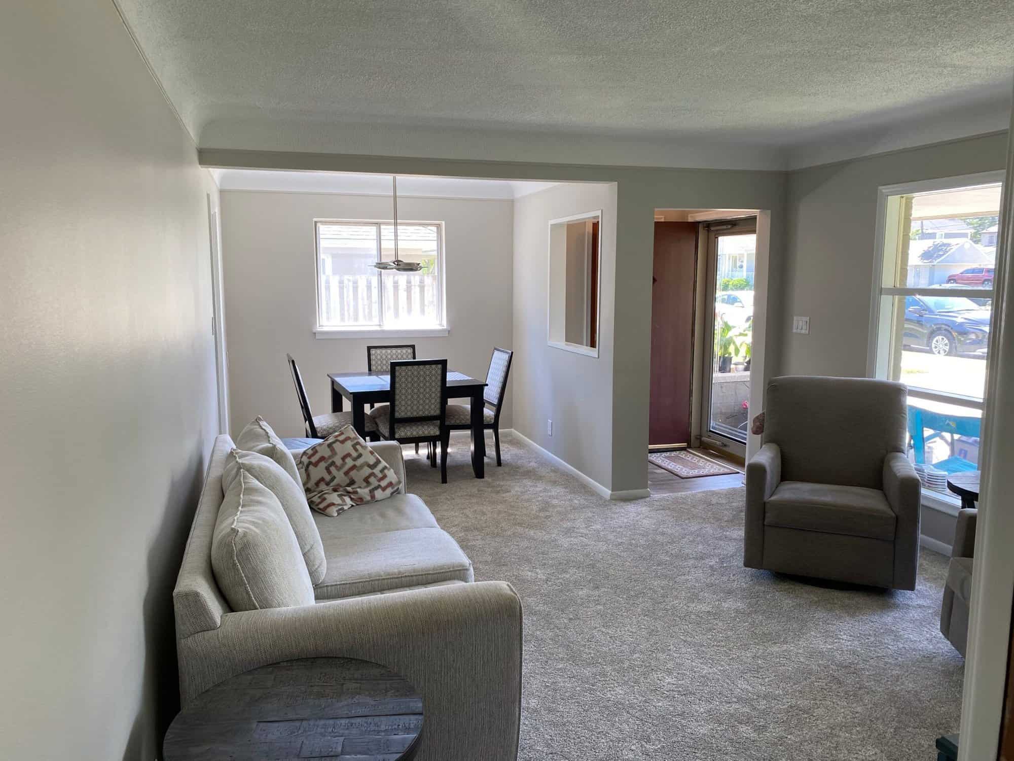 Greige-painted living room walls with white trim, gray carpet, cream upholstered furniture, and glass patio doors in Royal