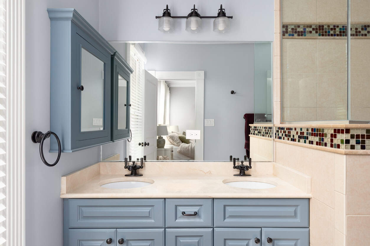 A bathroom with blue cabinets, granite countertop, and tiled shower.