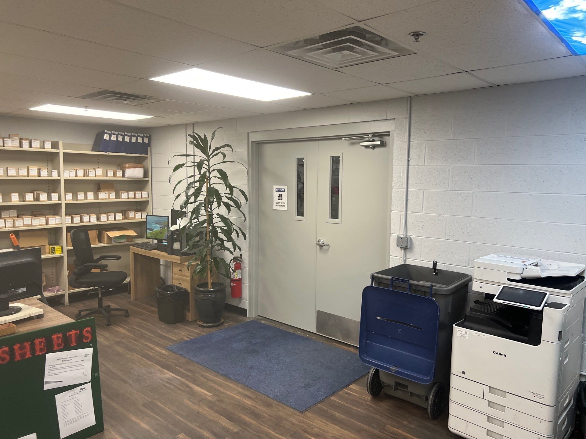 Clean commercial office space with freshly painted white block walls, wood flooring, and organized shelving.