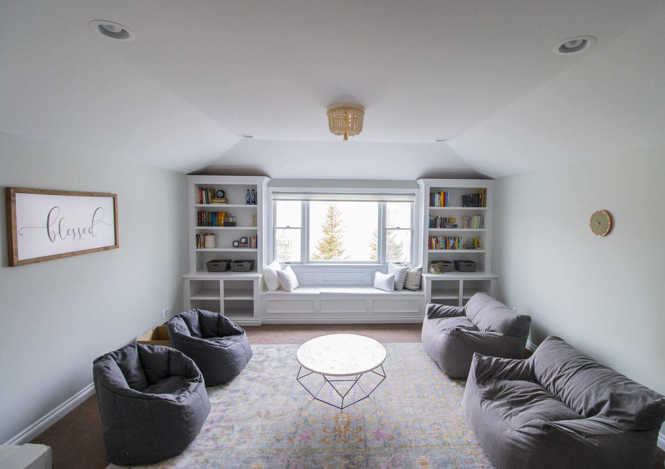 White-painted bonus room with vaulted ceiling, recessed lighting, built-in bookshelves, and window seat in Royal Oak
