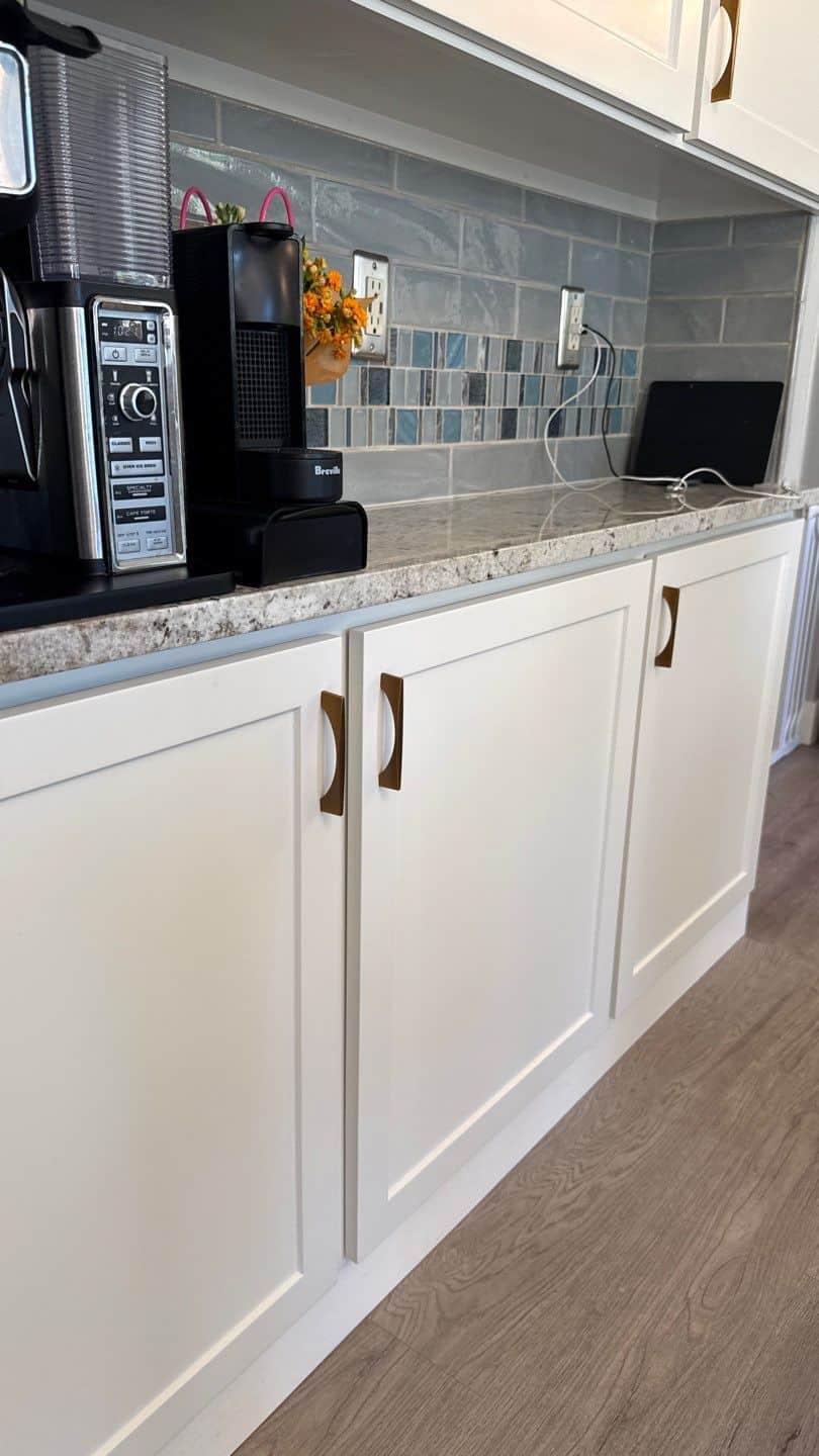White Painted Kitchen Cabinets White-painted recessed panel kitchen cabinets with bronze hardware, speckled granite countertop, and gray subway tile