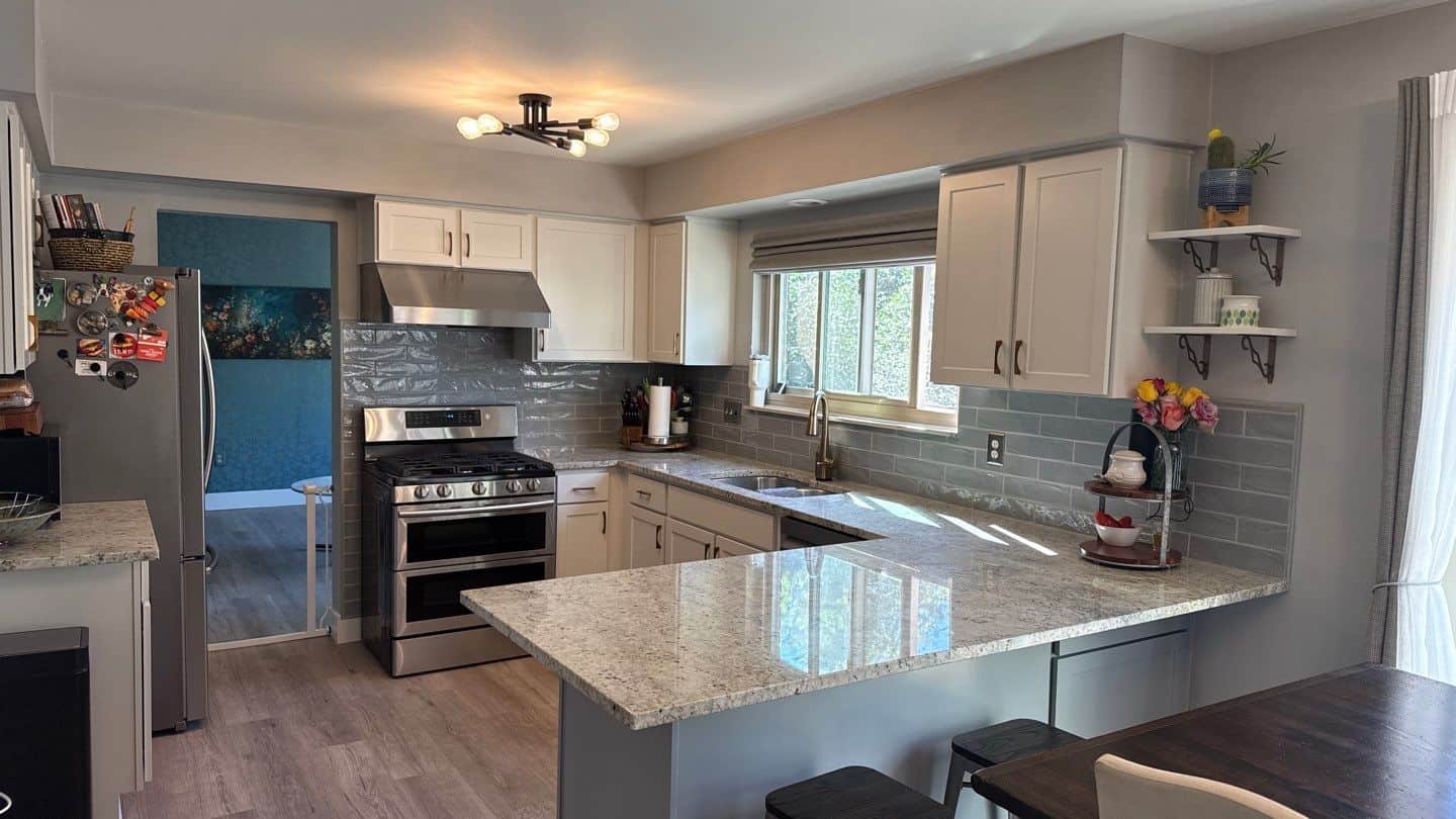 Cream Kitchen Cabinets Royal Oak Cream-painted kitchen cabinets with recessed panel doors, stainless steel hardware, speckled granite countertop, and gray