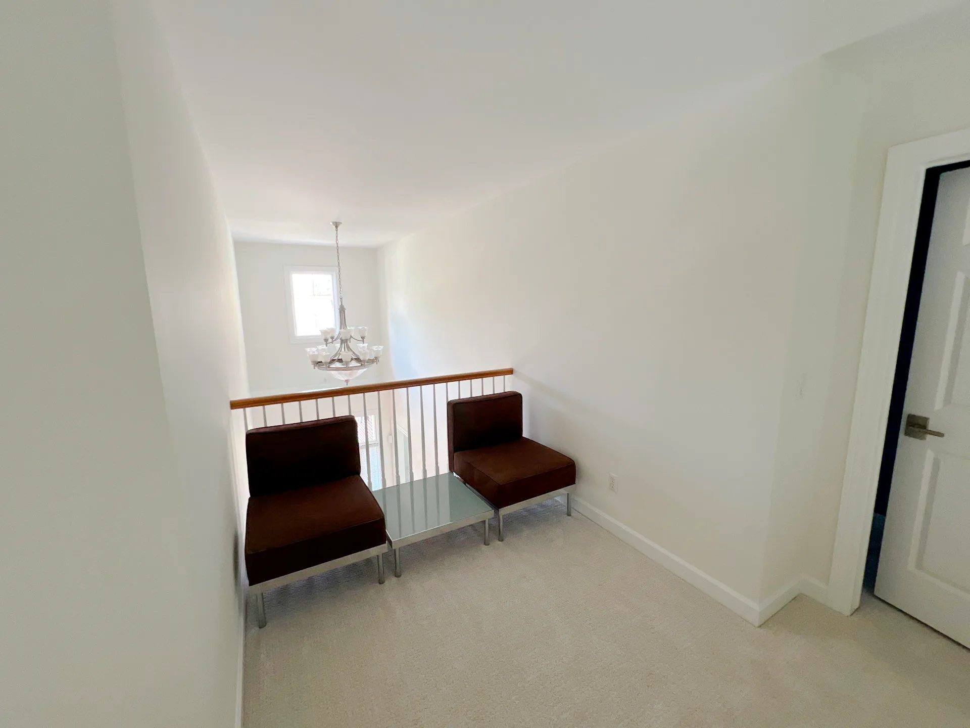 Bright white-painted loft room with metal railing, pendant lighting, and modern furnishings in Royal Oak