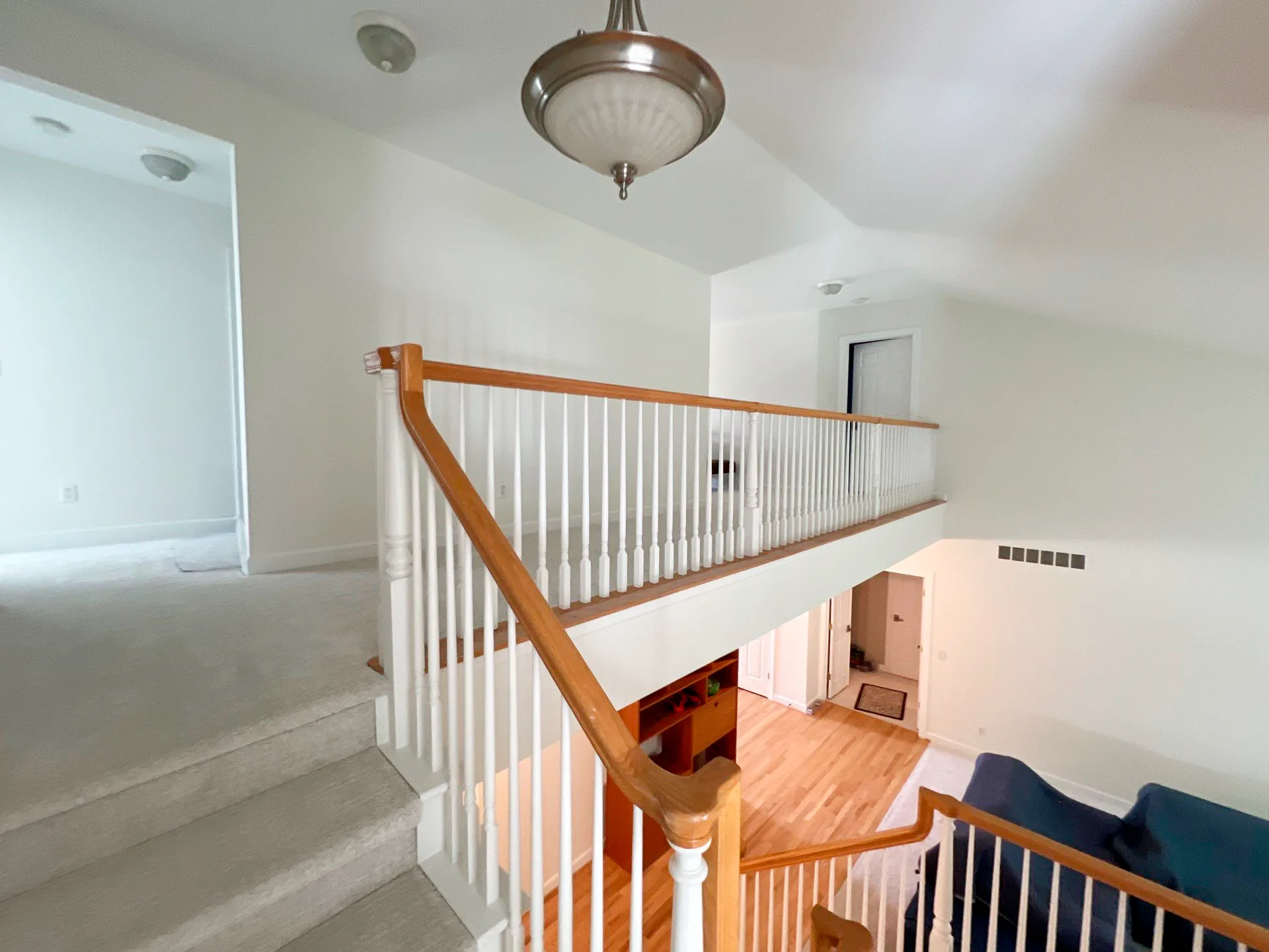 White Painted Staircase with Wood Handrail White-painted interior staircase with cherry wood handrail, white balusters, and wood flooring in Royal Oak home
